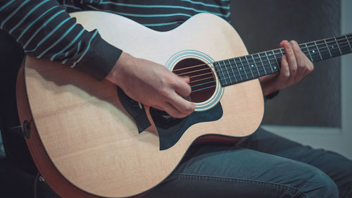 Midsection of man playing guitar