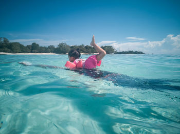 Girl swimming in sea against sky