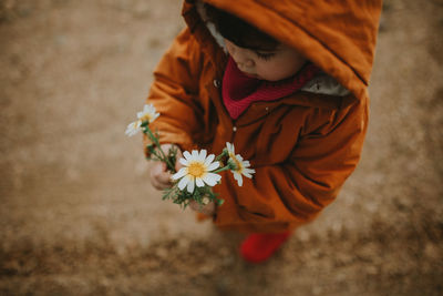 High angle view of girl holding flowers while standing in puddle