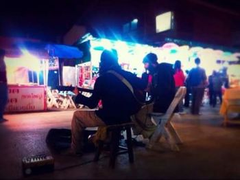 Men sitting on chair in city at night