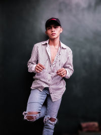 Portrait of young man standing against black background