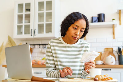 Portrait of young woman using laptop at table