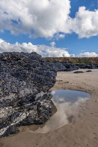 Rock formations on beach against sky