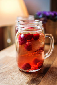 Raspberries in juice jar on table