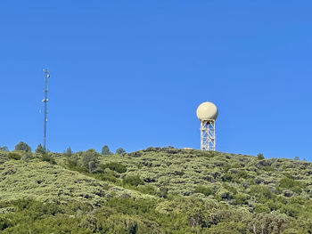 Low angle view of communications tower against clear blue sky