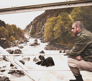 Side view of young man looking at bridge