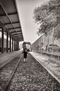 Man waiting at railroad station against sky