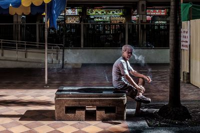 Portrait of man sitting on seat against building