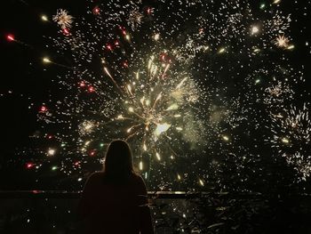 Rear view of woman looking at firework display at night