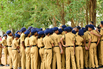 Children wearing police uniforms standing against trees