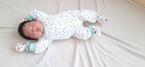 High angle view of baby sleeping on bed