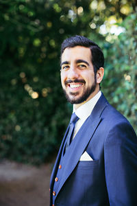 Portrait of smiling bridegroom standing in park