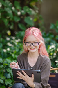 Young woman using mobile phone while sitting outdoors