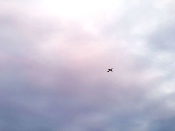 Low angle view of airplane flying against cloudy sky
