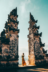 Woman standing amidst built structure at temple against sky