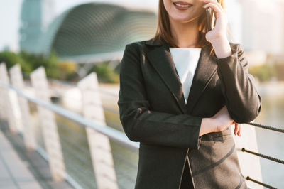 Portrait of young woman standing against railing