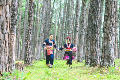 People standing by tree trunks in forest