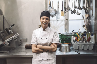 Portrait of smiling female chef with arms crossed in commercial kitchen