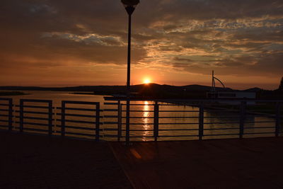 Silhouette pier over sea against sky during sunset