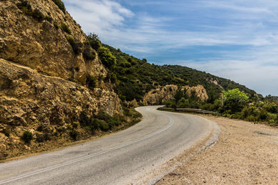 Empty road amidst mountains against sky