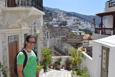 Portrait of young man standing against buildings in city