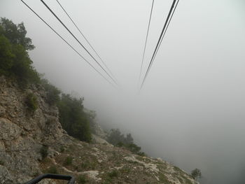 Overhead cable car over mountains against sky