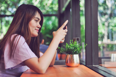Young woman using smart phone sitting at table 