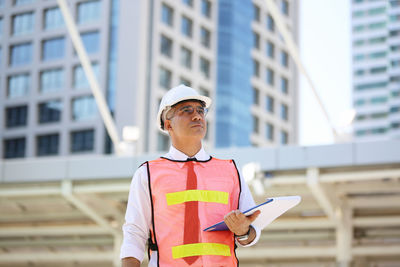 Man holding umbrella against building
