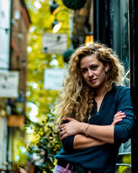 Portrait of beautiful young woman standing against city in background