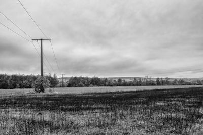 Electricity pylon on field against sky