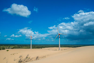 Scenic view of beach against sky and wind energy