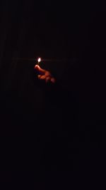 Person holding lit candle in the dark
