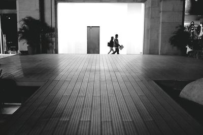 Man and woman walking on street seen through building