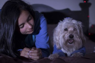 Portrait of woman with dog on bed