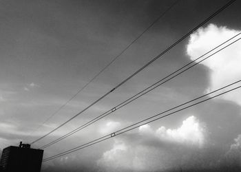 Low angle view of power lines against cloudy sky