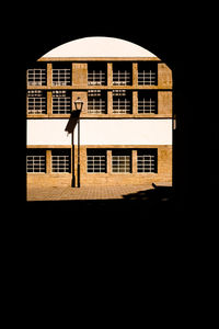 Silhouette man standing by building in city