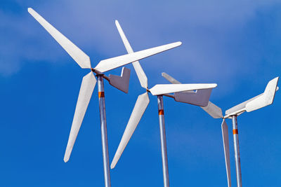 White wind turbines producing alternative energy on blue sky