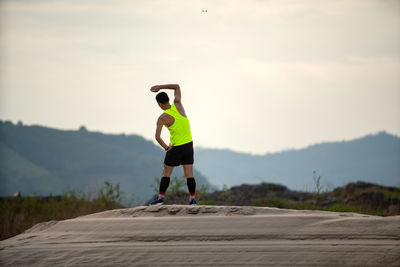 Rear view of man skateboarding on mountain against sky