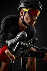 Close-up of man with bicycle against black background