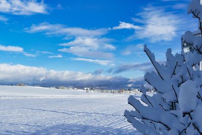 Snow covered landscape against blue sky