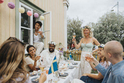 Happy male and female friends toasting wine during dinner party at cafe