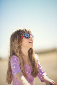 Portrait of young woman wearing sunglasses against sky