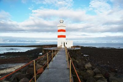 Lighthouse by sea against sky