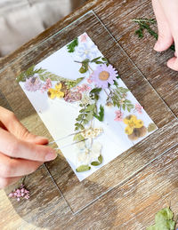 High angle view of woman hand holding white flower on table