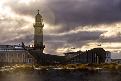 View of lighthouse by sea against buildings