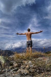 Rear view of shirtless man standing against sky