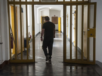 Rear view of man walking in corridor of building