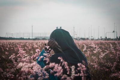 Close-up of woman standing in flowering field against sky