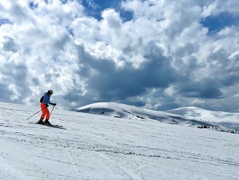 Woman skier going down the slope with mountains in the background