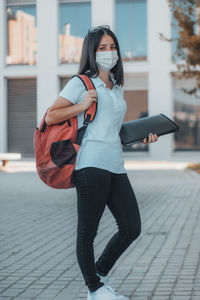 Portrait of young woman wearing mask standing on street